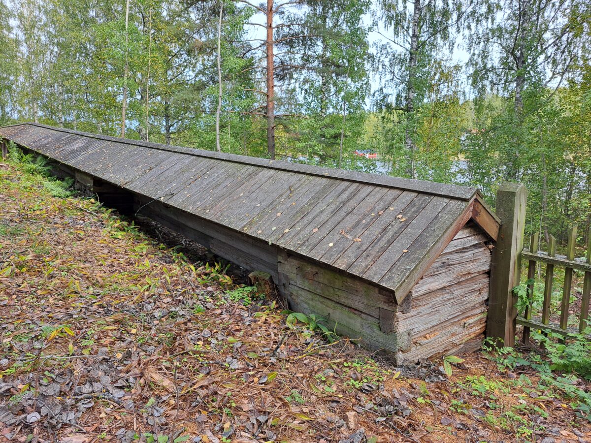 Kuva harvinaisesta hirsiarkkuaidasta, joka näyttää hirsistä tehdyltä paksulta aidalta, jonka päälle on tehty laudoista katto.